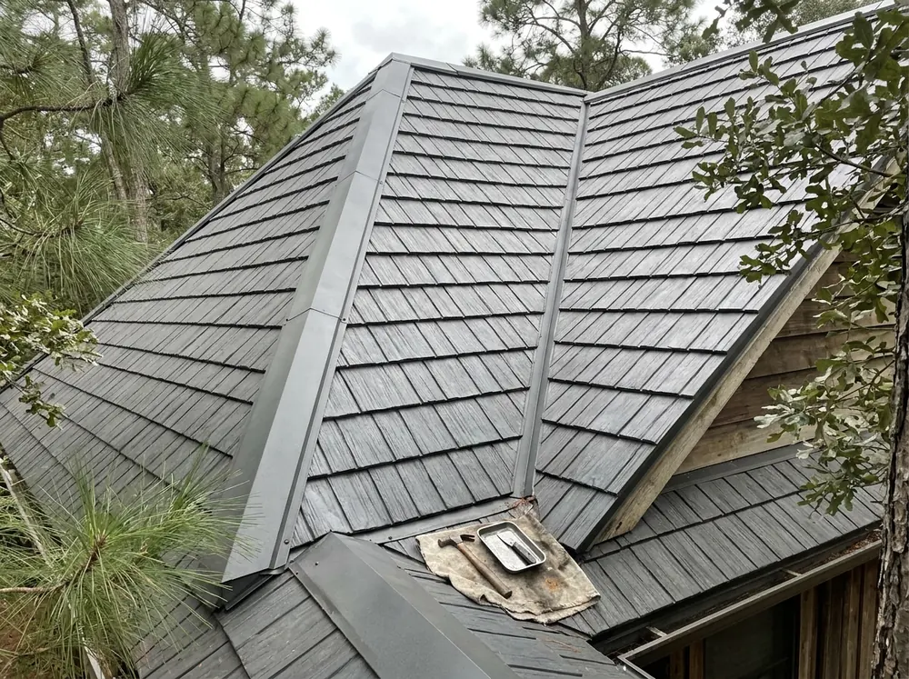 Dark gray aluminum shingle panels with a shake texture on a steep cottage roof