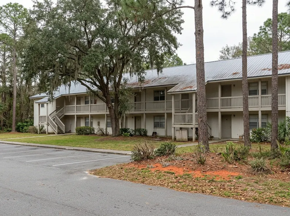 Two-story garden-style apartment building with a gray 5V metal roof and outdoor stair landings