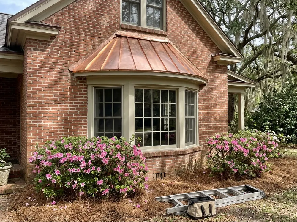 Small copper standing seam roof over a curved bay window on a red brick house