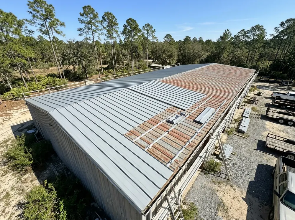 New standing seam panels on raised clips installed over old ribbed metal roofing on a shop building