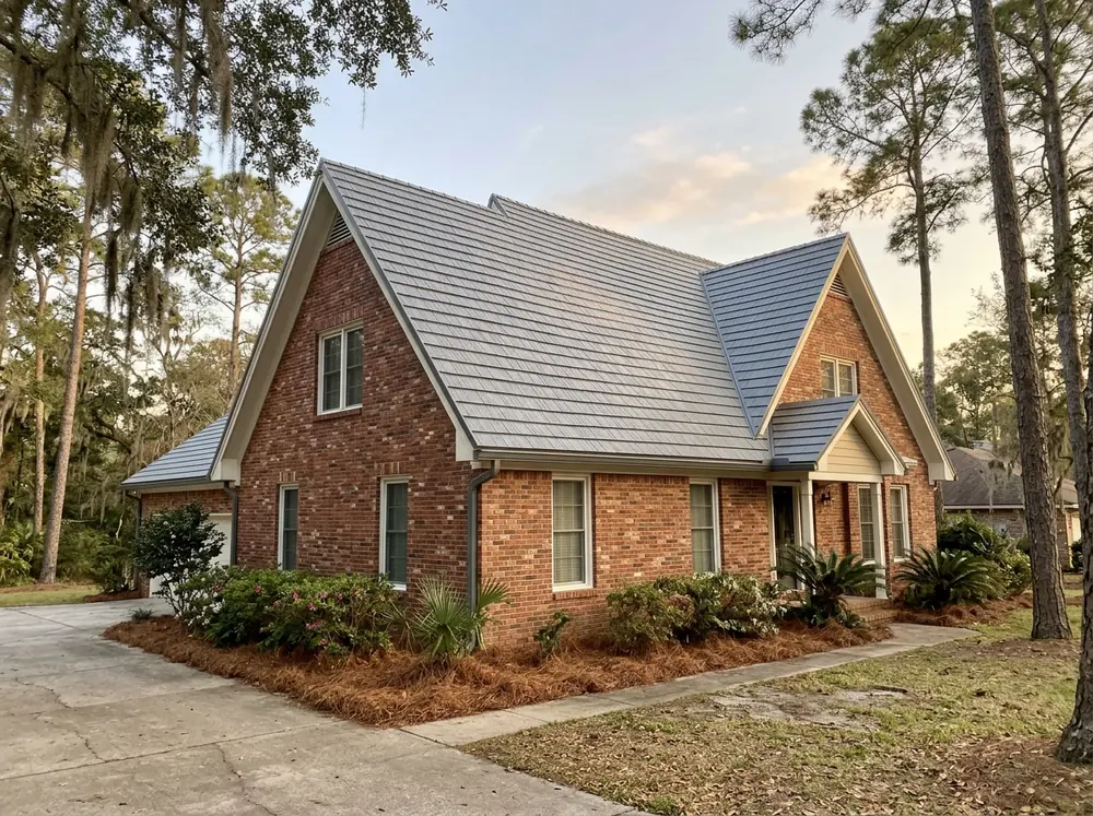 Gray steel shingles pressed in a slate pattern on a steep two-story brick house
