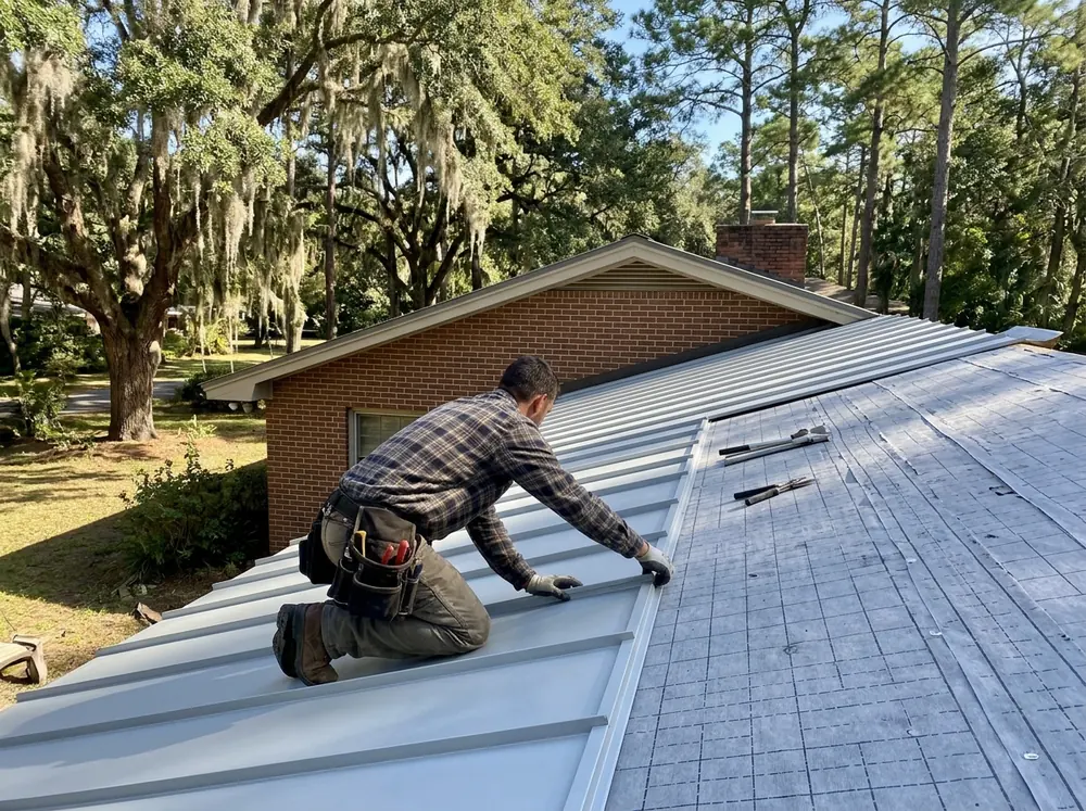 Installer pressing the edge of a snap-lock standing seam panel onto the one beside it over gray underlayment